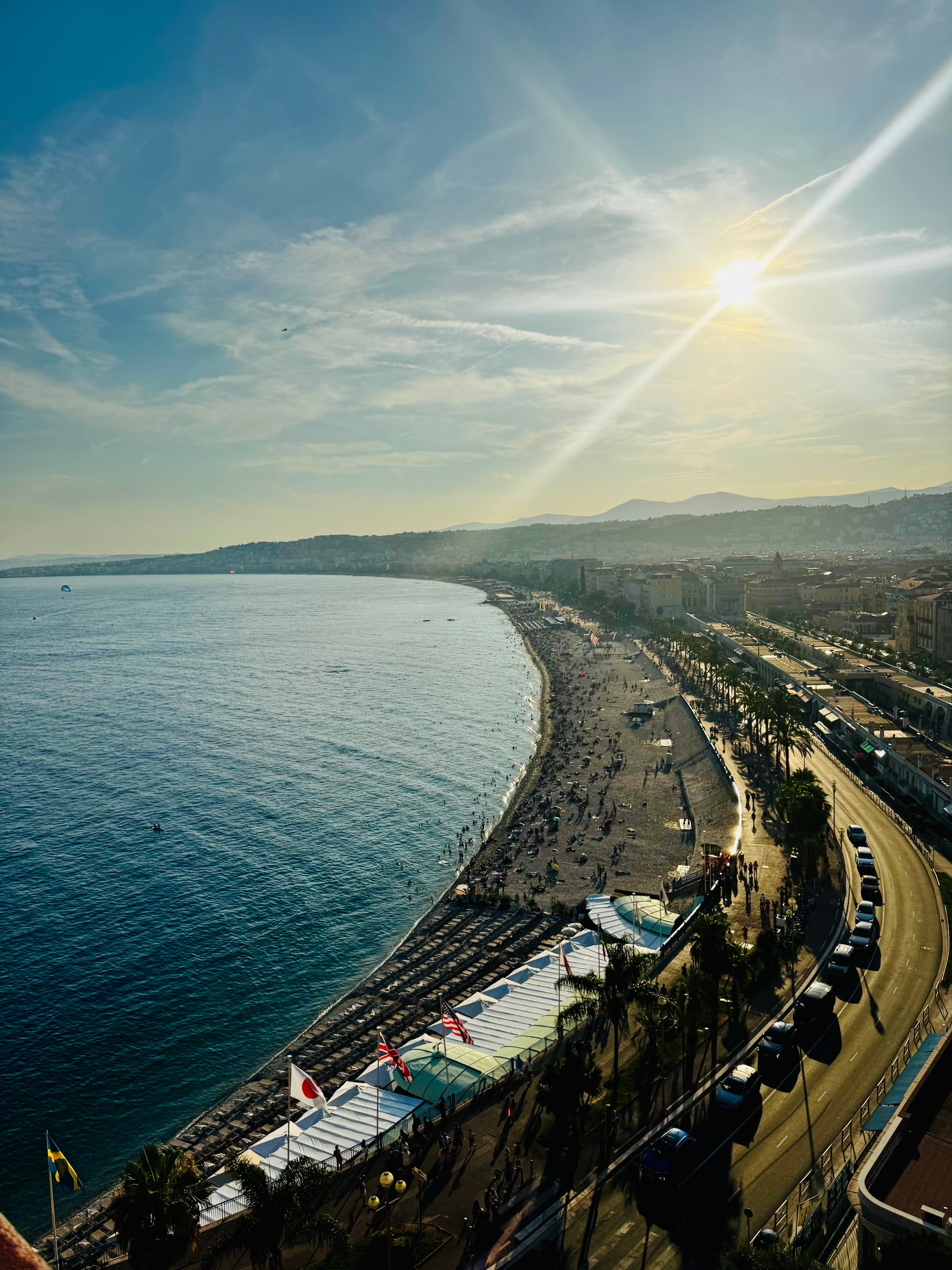 An aerial view of a curved coastline and beach promenade in late afternoon light
